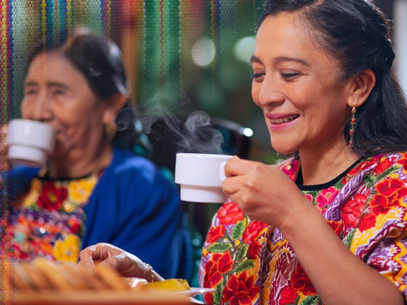 Two Peruvian women drink from teacups.