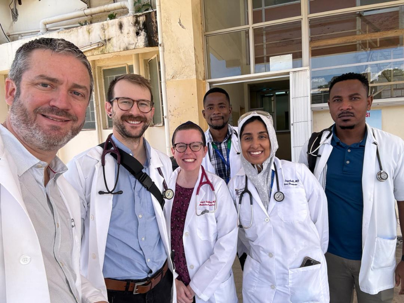 Students and faculty in white coats pose outside hospital in Zambia