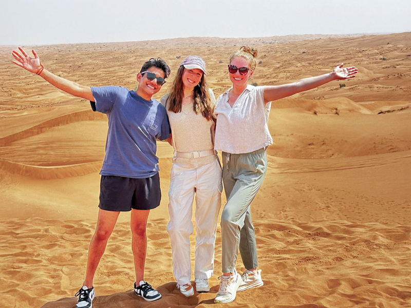 Three students pose for a photo in a Zambian desert.