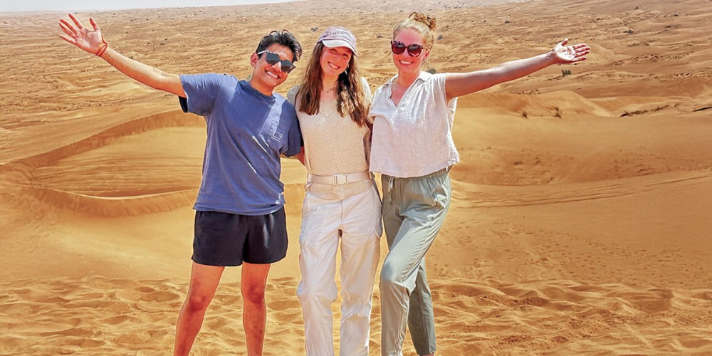 Three students pose for a photo in a Zambian desert.
