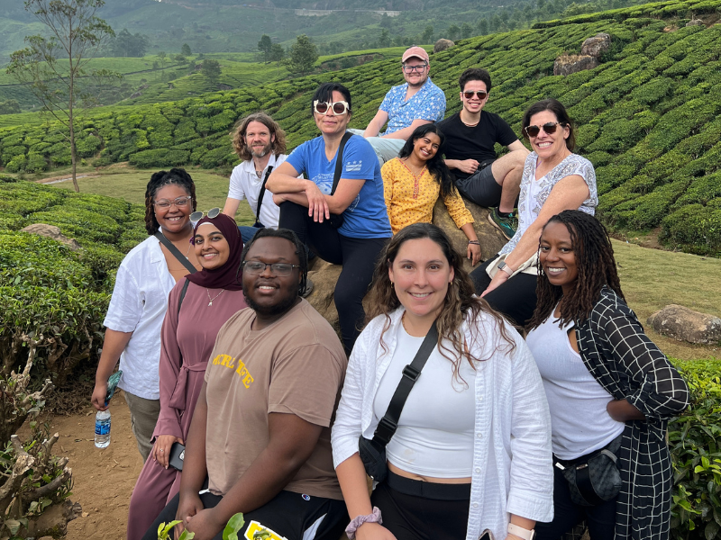 Students and professor pose for a group shot outside in a field.