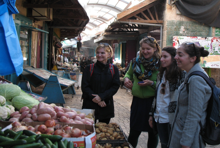 Young women admire a vegetable stall in a market
