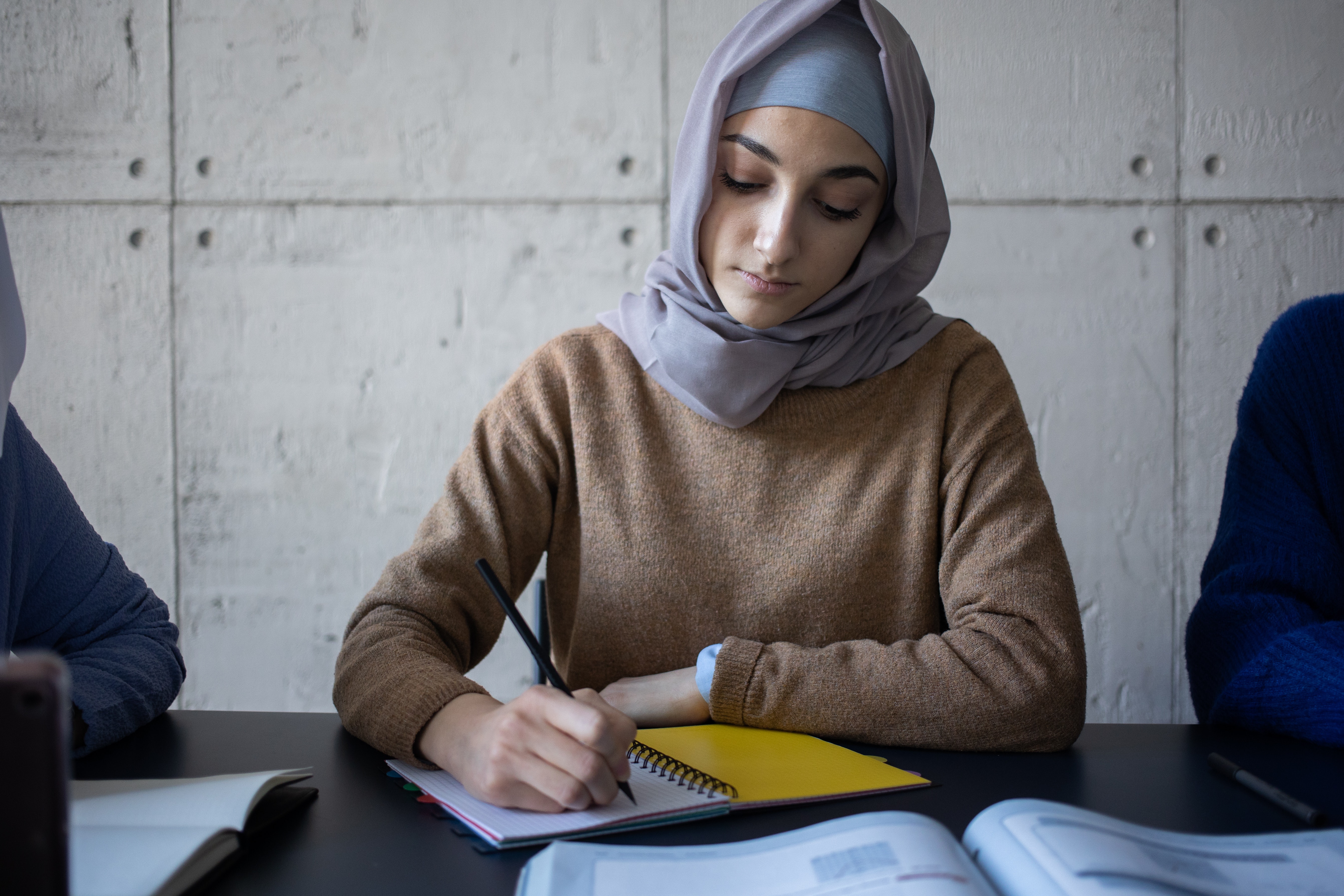 Woman with a headscarf writes in a notebook