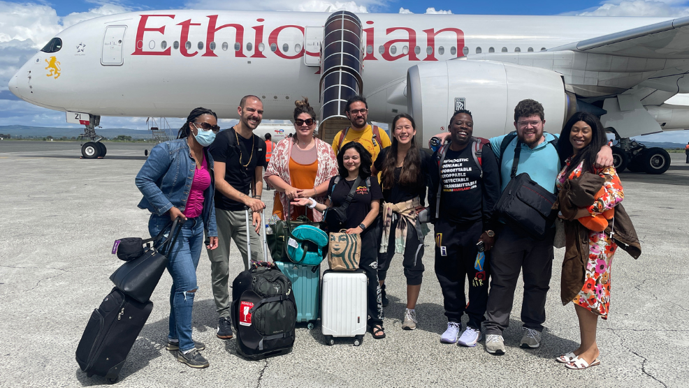 Students and faculty pose for a photo in front of an airplane