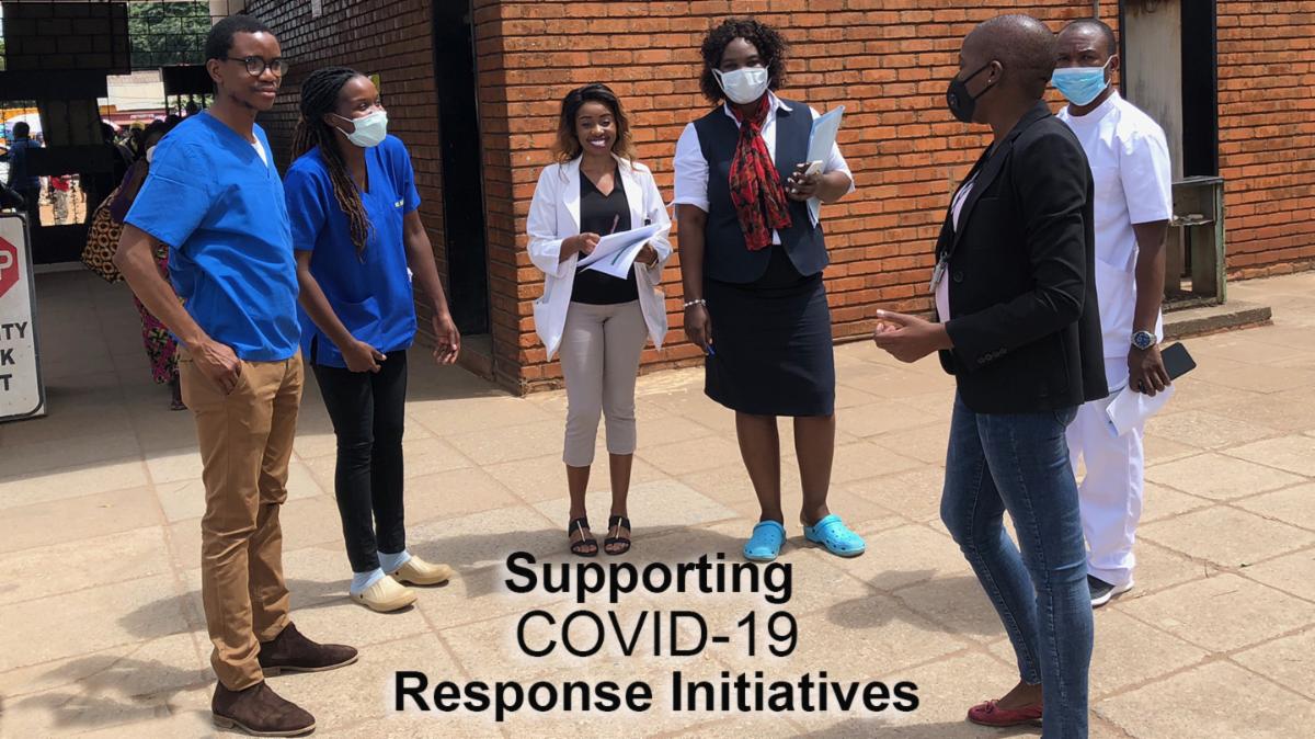 People standing outside a brick building wearing surgical masks.