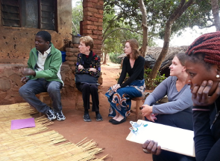 Group of people sitting on stools outside