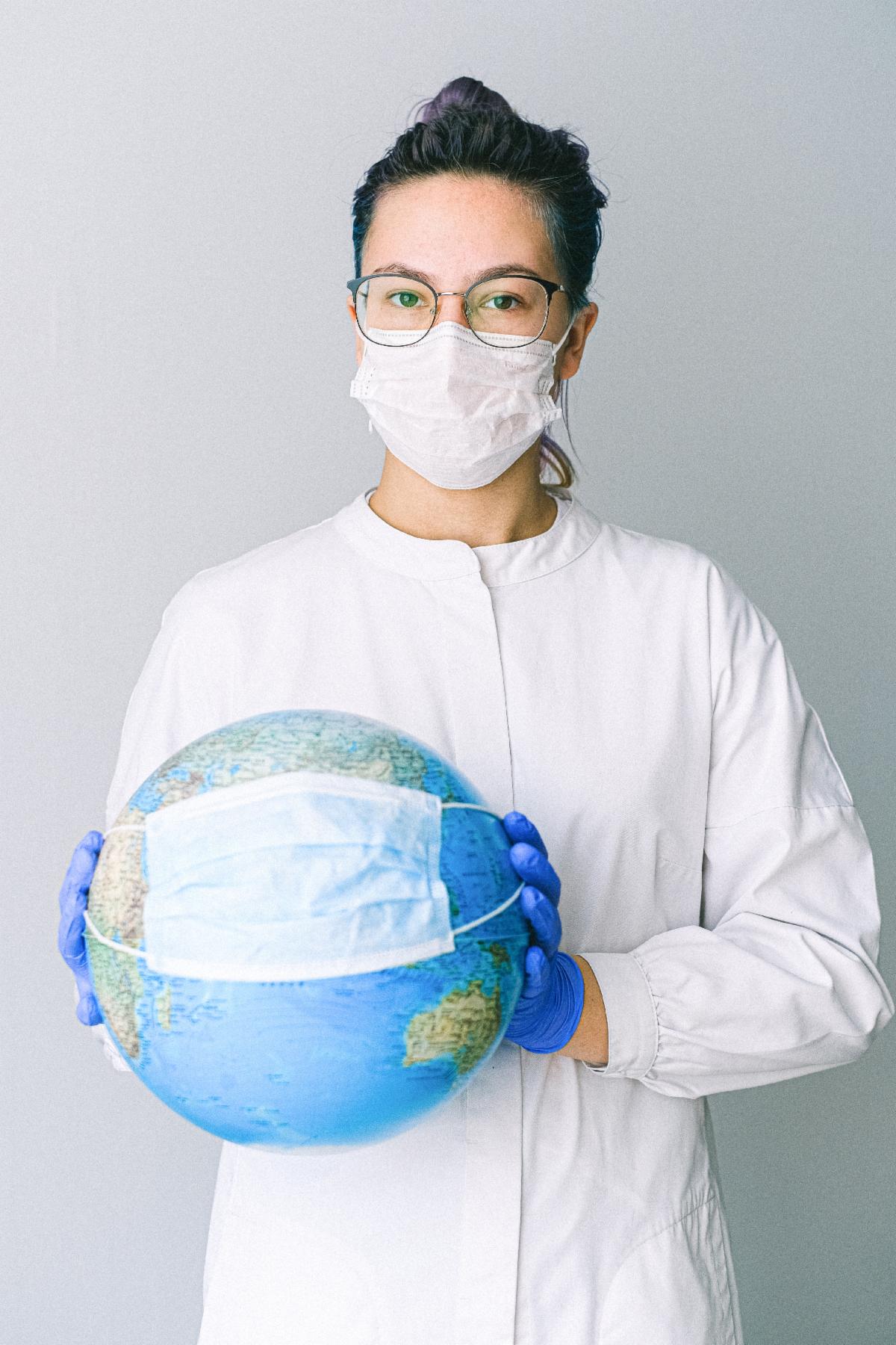 A person in medical gear wearing a globe with a mask over it