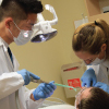 Dental students work a patient