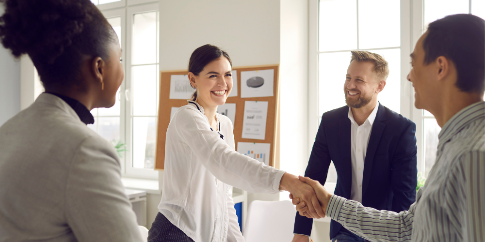 A woman smiles and shakes hands with a man