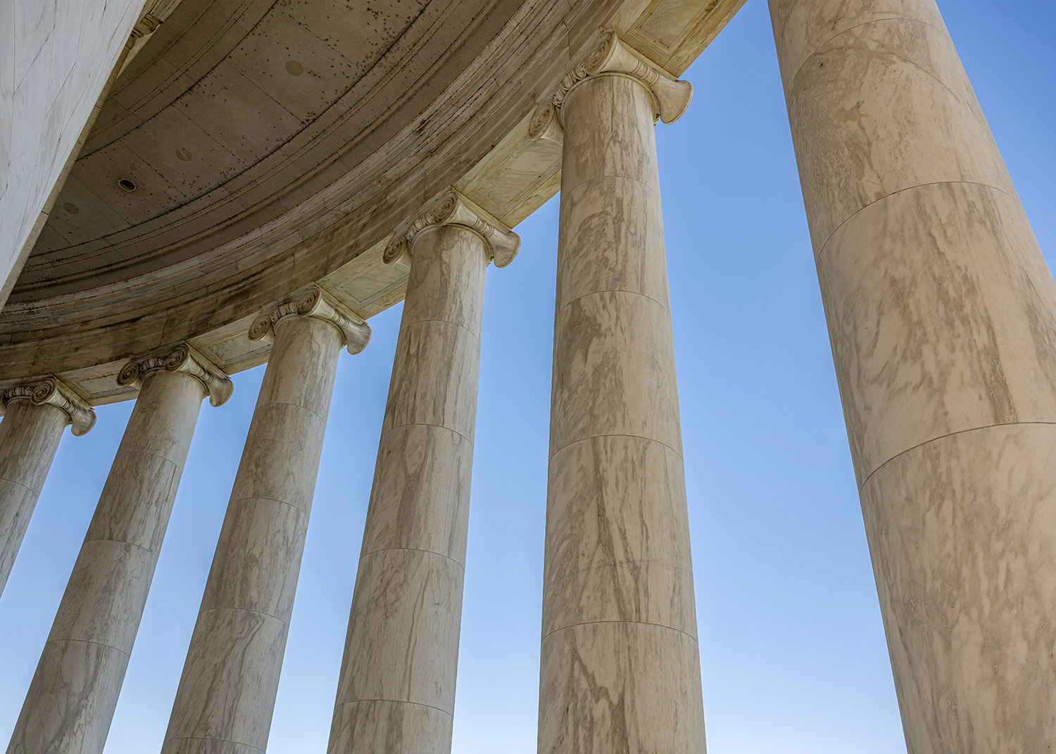 very large columns of a building against a brilliant blue sky