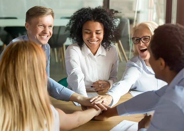 a group of professionals put hands together to celebrate accomplishments