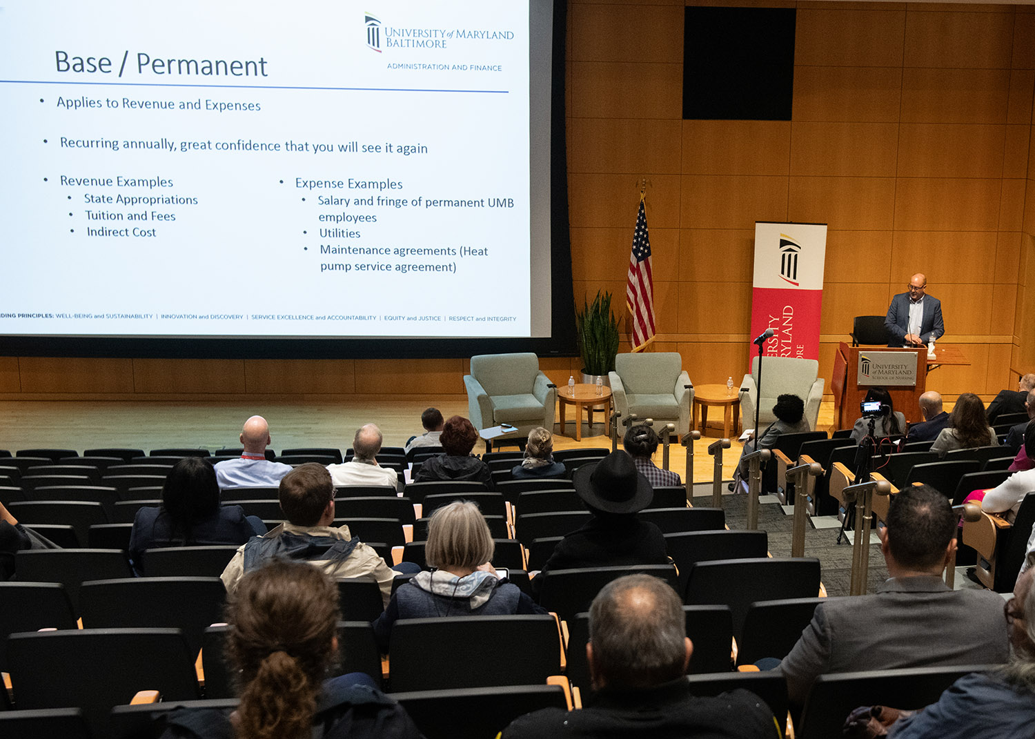 auditorium of people listen to budget presentation