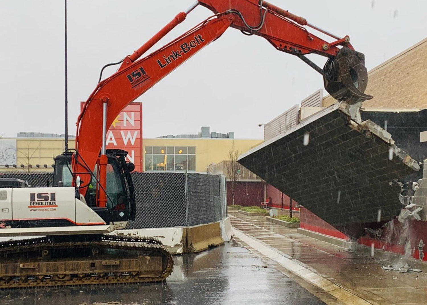 large construction vehicle pulls down concrete wall
