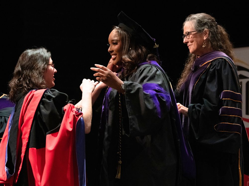 Profs. Leigh Goodmark and Kathleen Hoke hood a Maryland Carey Law graduate.