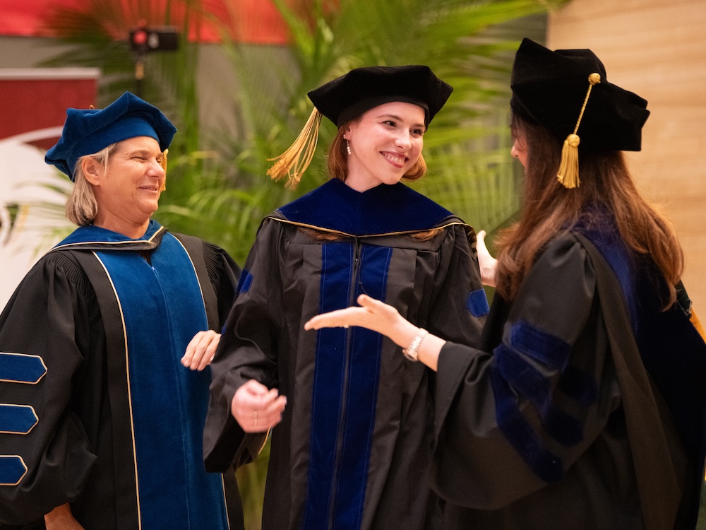Doctoral candidates on stage during 2026 Doctoral Hooding at UMB.