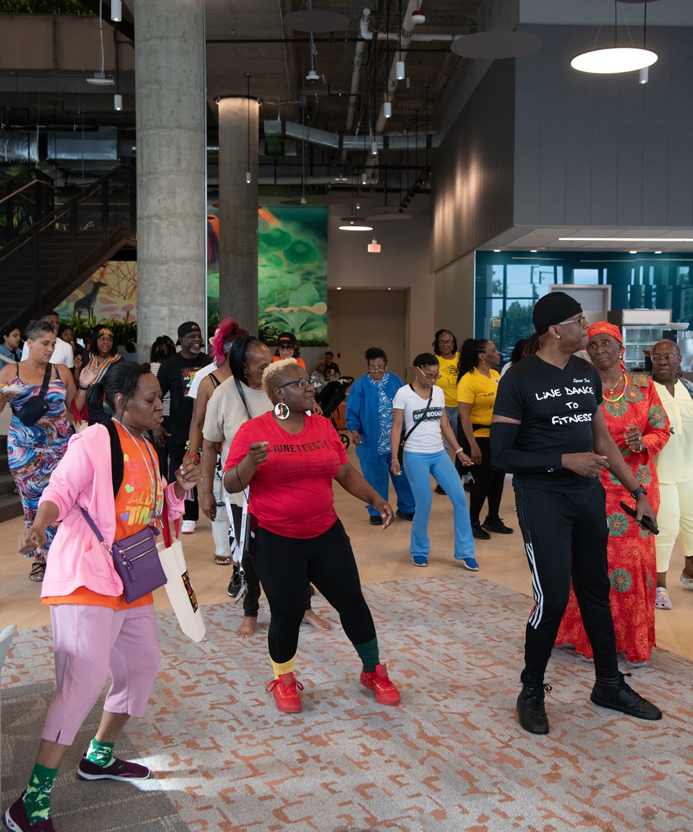 Community members line dance together during UMB's Juneteenth Jubilee at 4MLK.