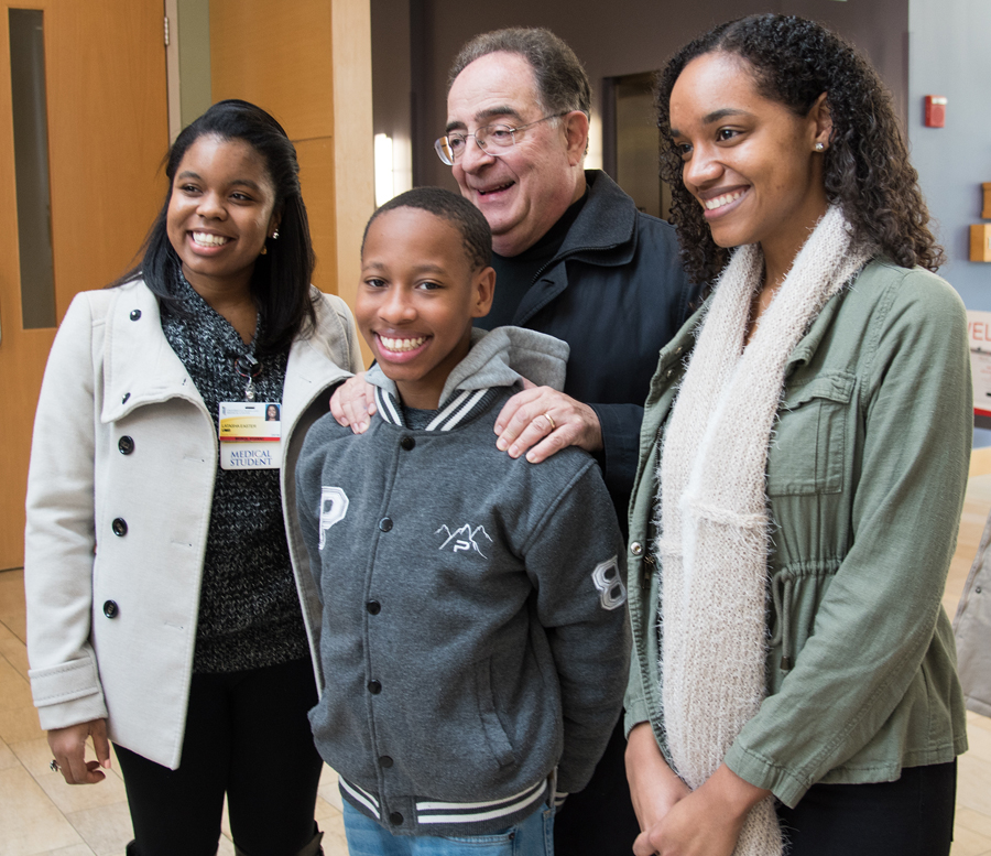 President Jay A. Perman, MD, greets UM School of Medicine students Latasha Easter, left, and Danielle Day, right, with eighth-grader Rocari Polk, a UMB CURE Scholar whom the students began mentoring as a sixth-grader. 