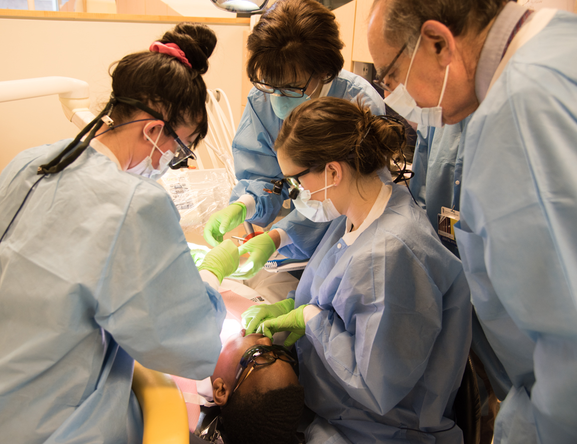 Barry L. Cohan, DDS ’74, right, joins dental hygiene students and faculty members during one of the oral health exams conducted for eligible UMB CURE Scholars as part of the School of Dentistry’s Oral Health Promotion Program. 