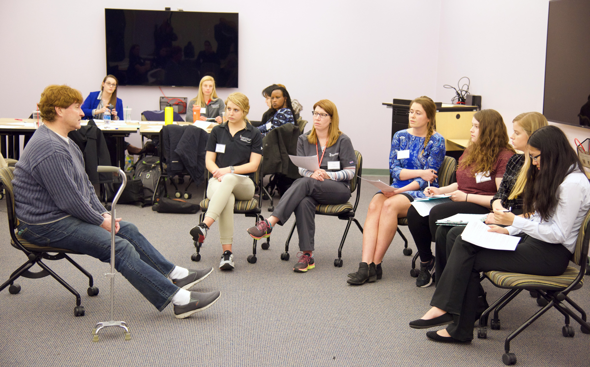 On IPE Day 2019, students practice teamwork across disciplines as they interview a standardized patient who has multiple sclerosis and faces housing and job issues.