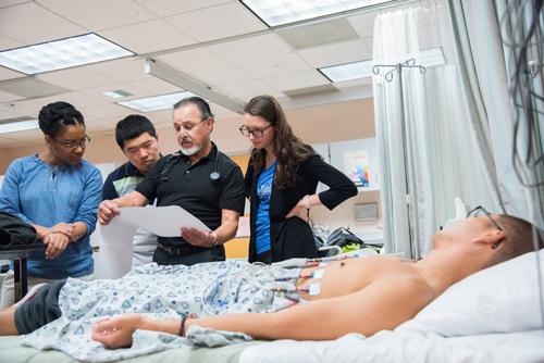 A UMB instructor teaches physician assistant students how to administer an electrocardiogram (EKG) at Anne Arundel Community College.