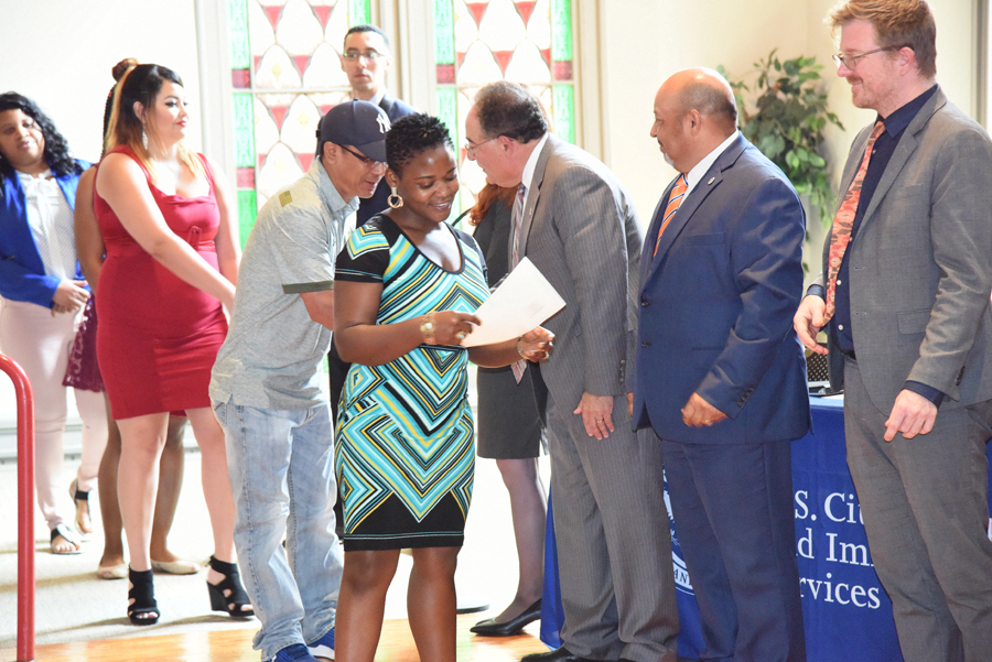 New U.S. citizen Endam Josephine Fombe, center, is greeted by, right to left, Luke Hall, section chief of U.S. Citizenship and Immigration Services (USCIS) Baltimore office; Conrad J. Zaragoza, field office director, USCIS Baltimore, and UMB President Jay A. Perman, MD, at the conclusion of a naturalization ceremony at Westminster Hall.