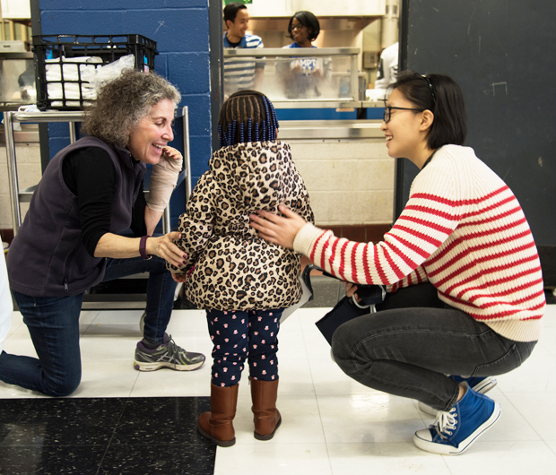 A child is greeted by School of Medicine student Jiun Yiing Hu, right, and Esta Glazer-Semmel, MSW, a clinical instructor in the school's Department of Psychiatry and an alumna of the School of Social Work. 