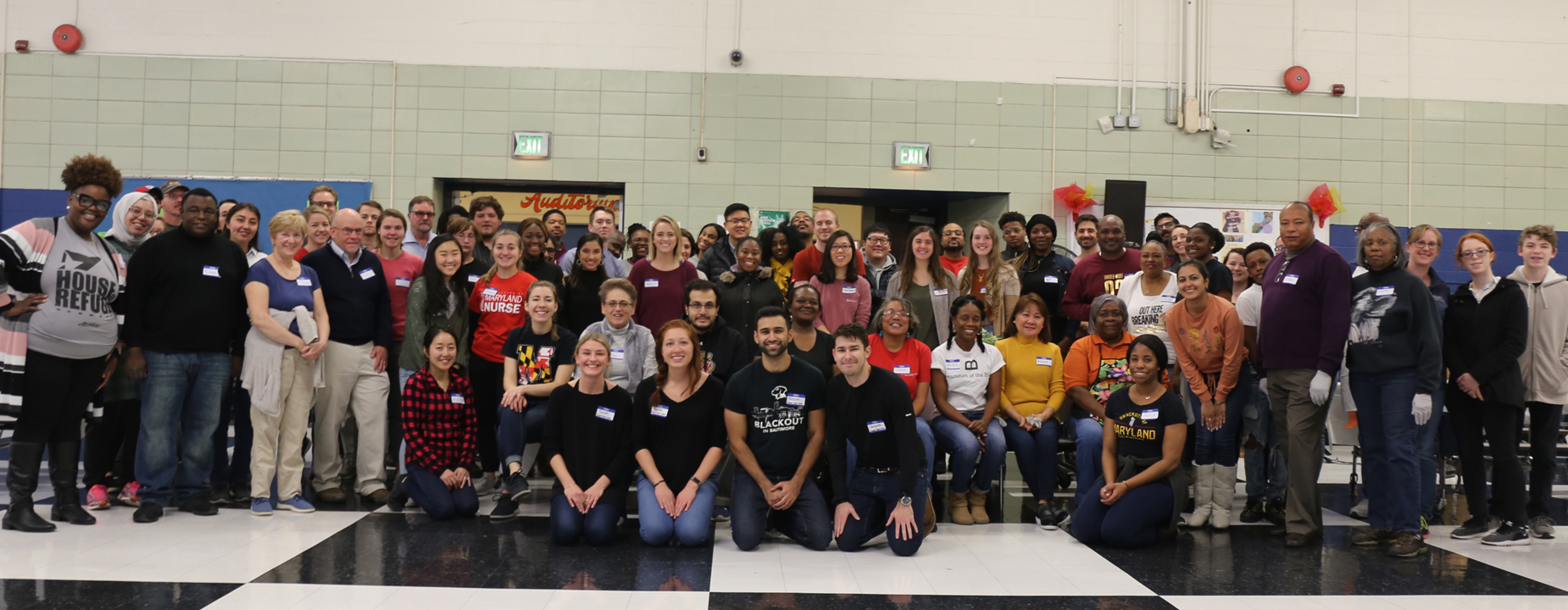 Dozens of 2019 Project Feast volunteers prepare to begin serving on Thanksgiving Day as they gather with School of Medicine organizers Sarah Heaps, Isabelle Lock, Nevin Varghese, and Stephen Semick, left to right, first row; and Rami Yanes, fourth from left, second row.