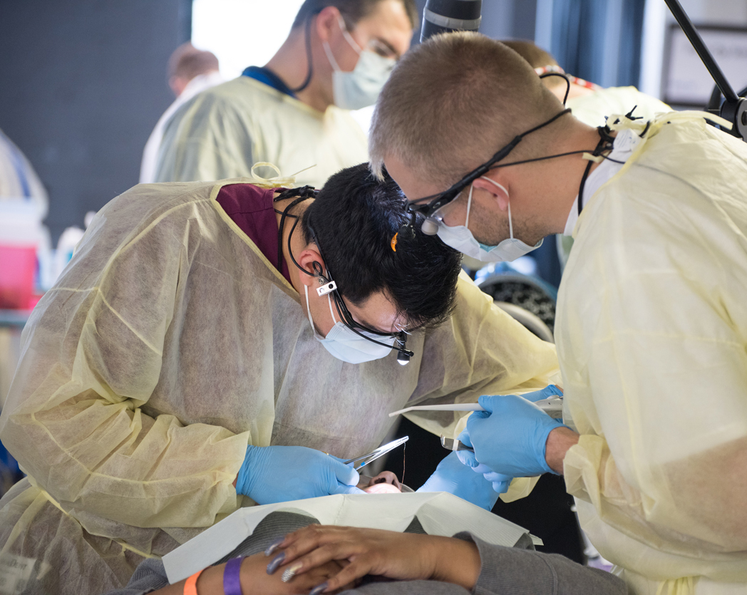School of Dentistry fourth-year student David Anguiano, left, shown completing treatment of a patient at Mission of Mercy, says: “One of reasons I pursued dentistry was to help others.