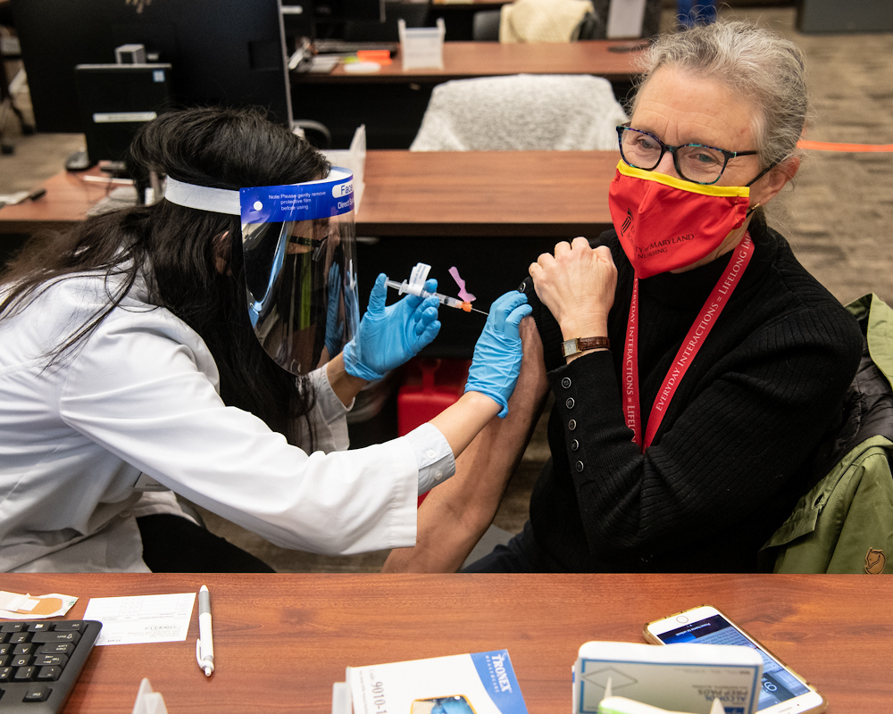 Jane M. Kirschling, PhD, RN, FAAN, dean of the University of Maryland School of Nursing, receives her first dose of the Moderna COVID-19 vaccine from University of Maryland School of Pharmacy student Amy Chen at the clinic established at the SMC Campus Center.