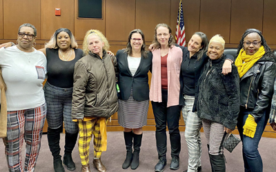 Leigh Goodmark, JD (center) poses with clients in the Maryland Carey Law Moot Courtroom.