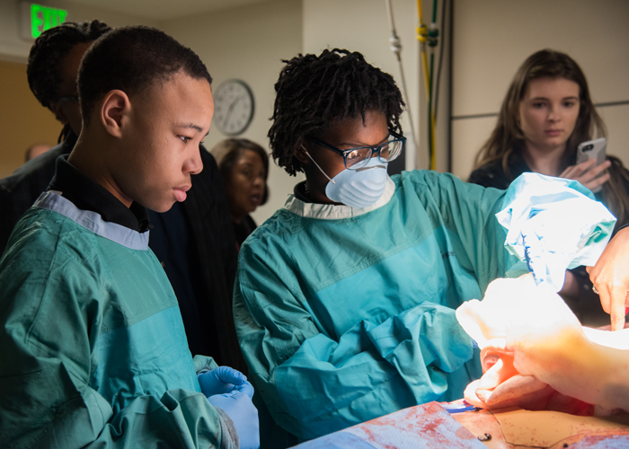 The P-TECH students learn how trauma surgeons prepare for emergency surgery with an exploratory laparotomy simulation on a medical mannequin.