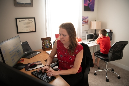 Carolyn Apanavage, BSN, RN-BC, CEN, of Managed Care Advisors works as a medical case manager for the UMB COVID-19 Hotline from her New Market home as her son, Brayden, attends virtual school in the background. Matthew Paul D'agastino/University of Maryland, Baltimore