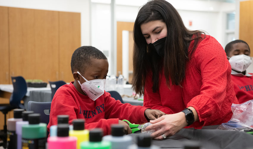 Anna Borgerding, UMB’s director of operational excellence and sustainability, helps Desmond Washington, a student at James McHenry Elementary School, create a planter out of a recycled water bottle. 
