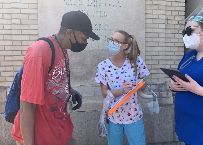 Maddie Boyes, RN (right), and Hayley Carper, RN (center), two students at the University of Maryland School of Nursing, help William Lipmann, a West Baltimore community member, get registered for a vaccine appointment.