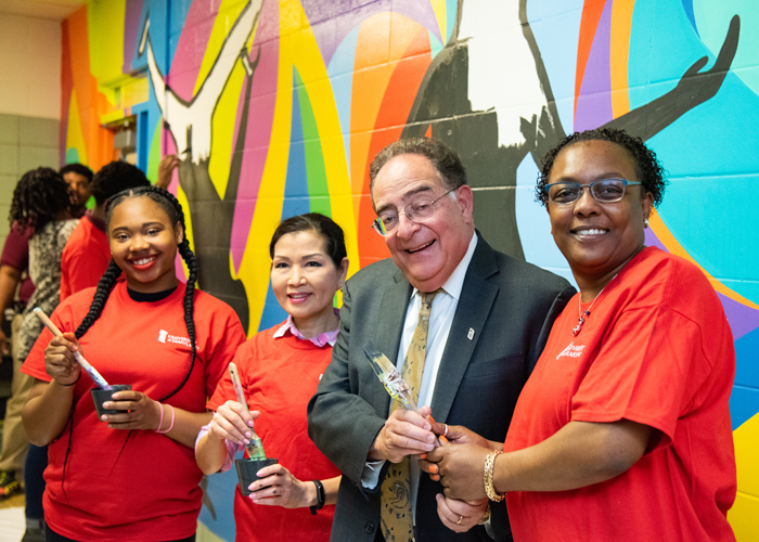 Taking a break from painting, (from left) Dyelle Washington, a sophomore at Renaissance Academy; Maryland First Lady Yumi Hogan; UMB President Jay A. Perman, MD; and Renaissance Academy principal Tammatha Woodhouse, pose for a picture in front of the colorful mural.
