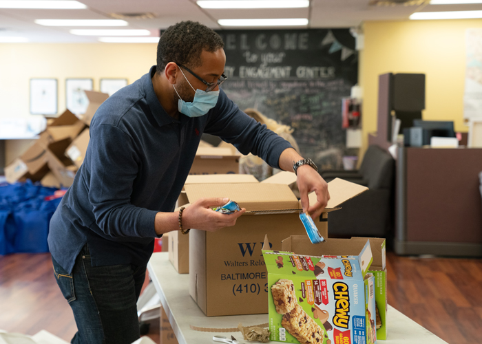 Borndavid McCraw, PAL Program coordinator at the UMB Community Engagement Center, stuffs care packages with donated supplies to be delivered to the families involved in the UMB PAL Program.