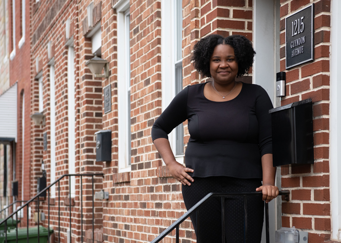 Rajaniece Thompson, a new homeowner through UMB's Live Near Your Work Program, stands in front of her new home in Pigtown.