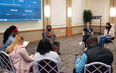 UMB students from various disciplines talk to a simulated patient (center) about her medical history at IPE Day.. 