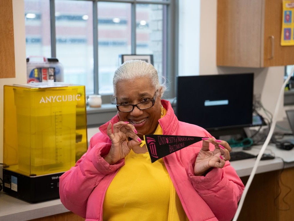 Community member Sandy Price holds a banner made at a recent class hosted through UMB’s collaboration with Open Works.