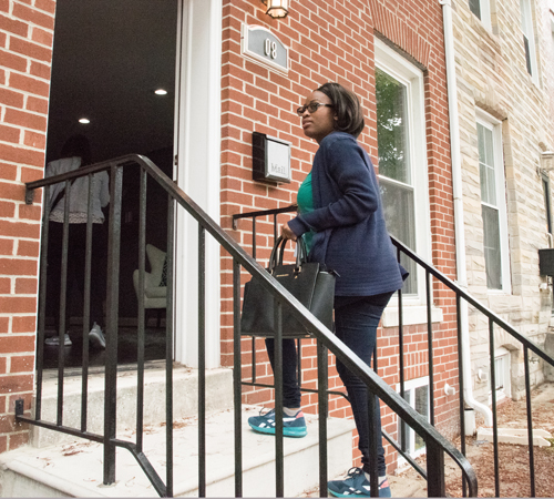 Toni-Ann Wiggan, a research technician at the University of Maryland School of Medicine, enters a Pigtown rowhouse on a tour of homes available for purchase through the Live Near Your Work Program at the University of Maryland, Baltimore.