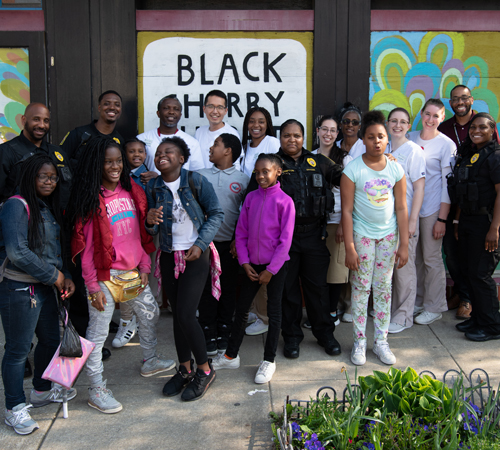 West Baltimore children, University of Maryland, Baltimore police officers and students from the University of Maryland School of Nursing stand outside the Black Cherry Puppet Theater after performing 