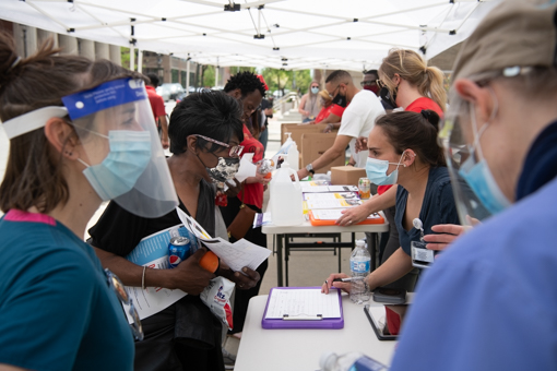 Students from the University of Maryland School of Nursing answer questions and get neighbors signed up for a COVID-19 vaccine appointment at the SMC Campus Center during the Community Engagement Center's free community lunch program.