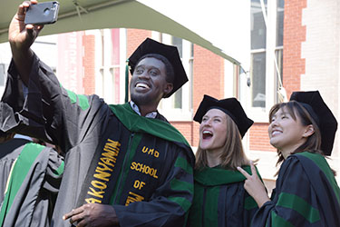 Paapa Nyanin, MD ’21, takes a selfie with classmates after the University of Maryland School of Medicine hooding ceremony. 