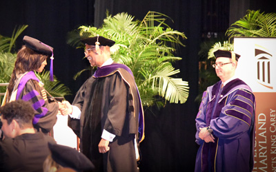 Carey Law convocation speaker Judge Roger L. Gregory congratulates a graduate as Dean Donald B. Tobin looks on. 