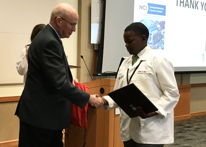 Kevin Cullen, MD, director of the Marlene and Stewart Greenebaum Comprehensive Cancer Center (left), presents Jaylen Galmore with a research award. 