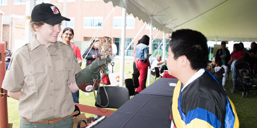 Naturalist Courtney Birkmeyer shares tales of the eastern screech owl's eating and behavioral habits with UMB Neighborhood Spring Festival goers and performers.