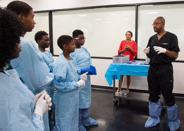Orthopedic surgeon Craig Bennett, MD (right), welcomes the UMB CURE Scholars to Supreme Orthopedic Systems Lab before showing them how to perform an ACL reconstruction on a cadaver’s knee.