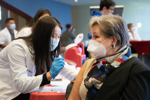 M.J. Tooey, associate vice provost and dean of the Health Sciences and Human Services Library. receives her flu shot from Katherine Tieu, a fourth-year pharmacy student.