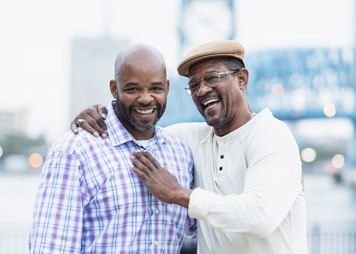 two men of different generations stand side-by-side in embrace, similing