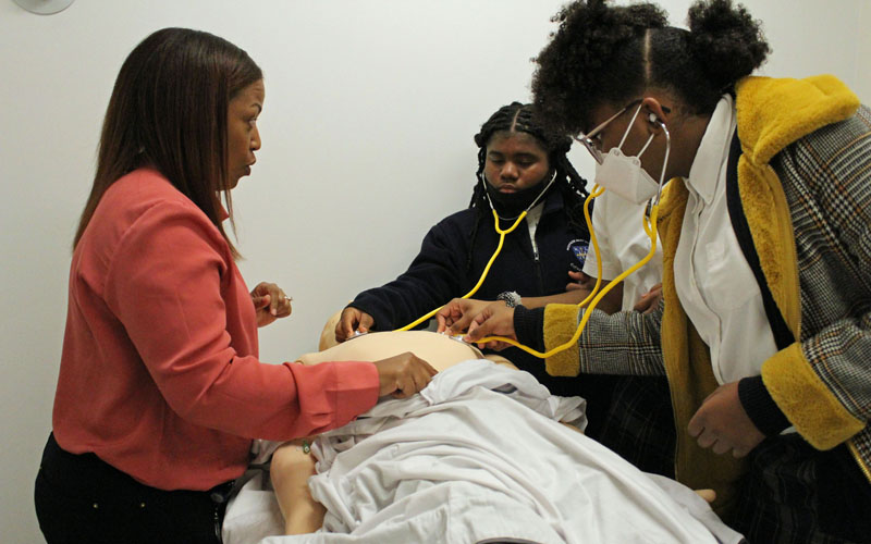 Kimberlee Bizzell, MD, medical director and assistant professor, UMB Physician Assistant Program, shows the Mother Mary Lange Catholic School students how to check a patient's heartbeat.